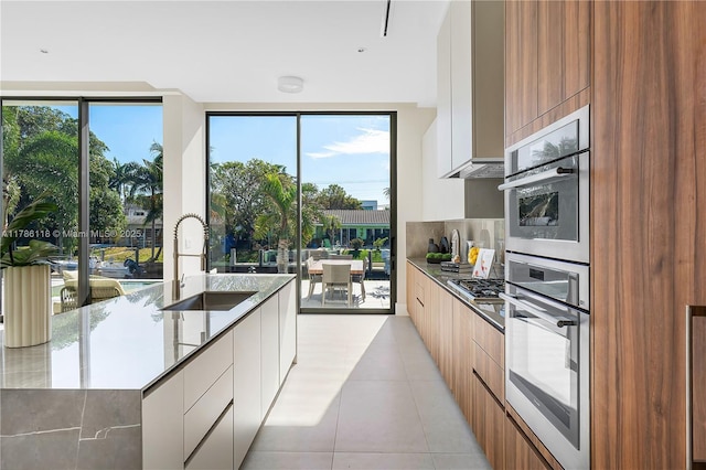kitchen with a sink, light tile patterned flooring, backsplash, modern cabinets, and appliances with stainless steel finishes