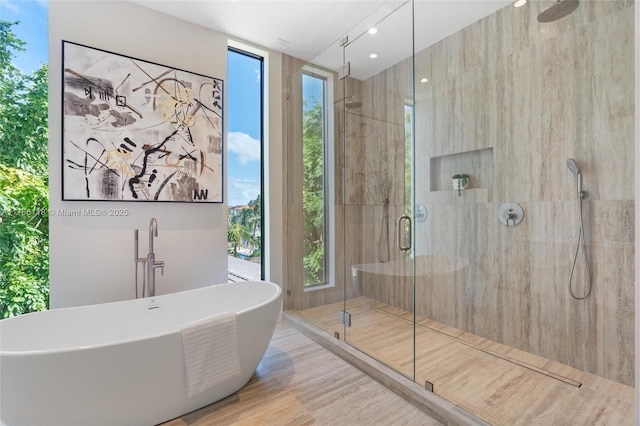 full bathroom with a freestanding tub, a wealth of natural light, and a stall shower