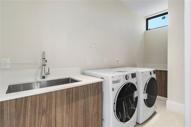 clothes washing area with independent washer and dryer, laundry area, and a sink