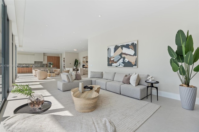 living area featuring concrete flooring and baseboards