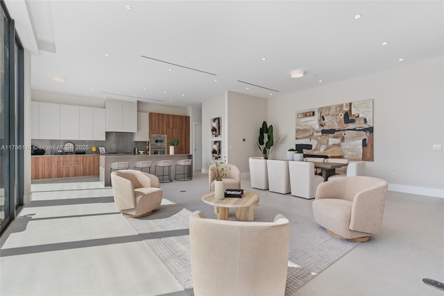 living room with baseboards, concrete flooring, and recessed lighting