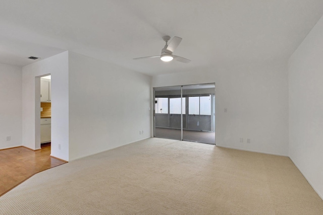 empty room featuring visible vents, a ceiling fan, and carpet floors