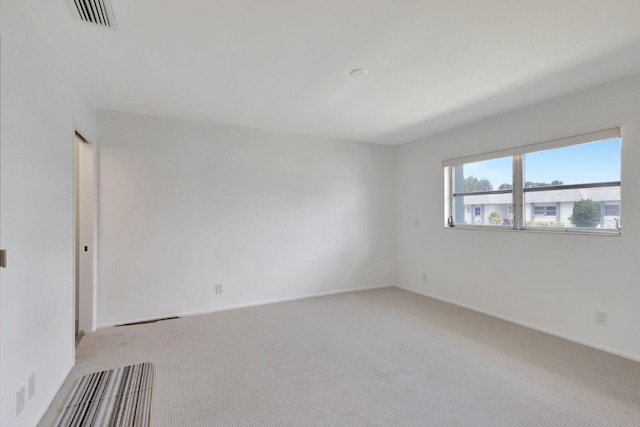 spare room with light colored carpet, visible vents, and baseboards