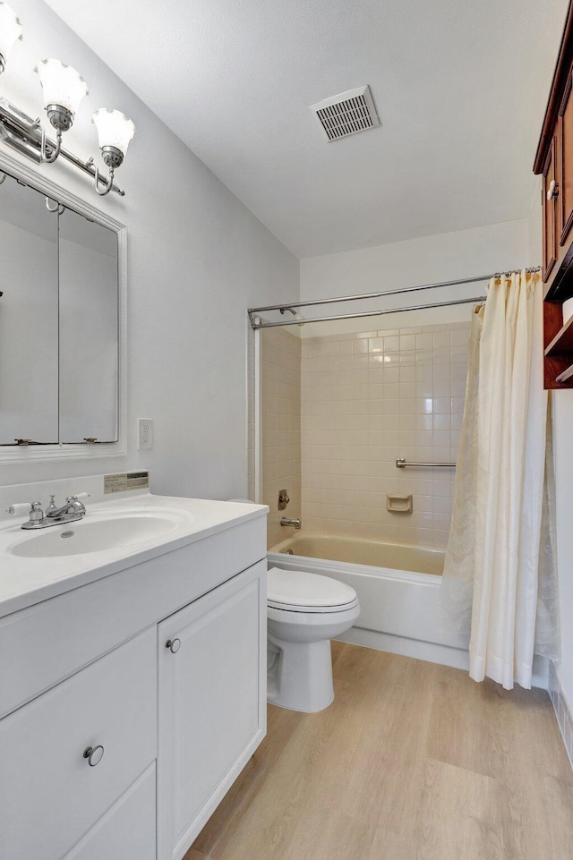 full bath featuring vanity, wood finished floors, toilet, visible vents, and shower / tub combo with curtain