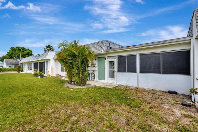rear view of property with a lawn and a sunroom