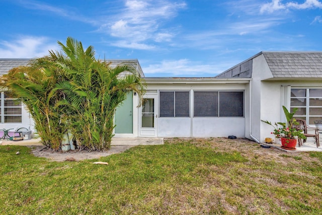 back of house with a lawn, stucco siding, and a sunroom