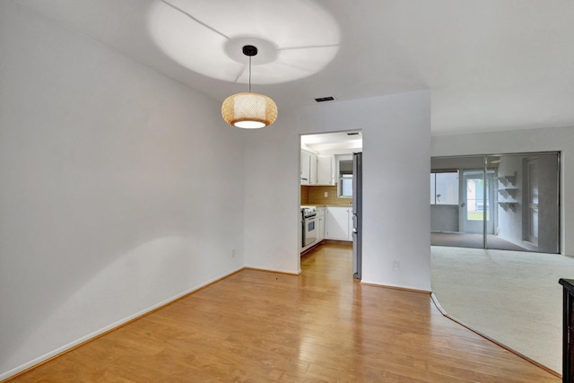 unfurnished dining area with visible vents, baseboards, and light wood-style floors