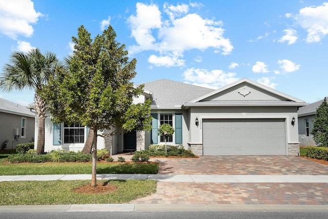 ranch-style house featuring stone siding, stucco siding, a garage, and decorative driveway