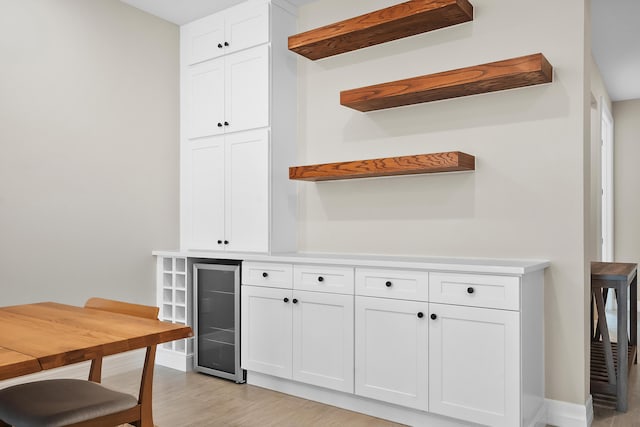 bar featuring baseboards, light wood-style flooring, and wine cooler