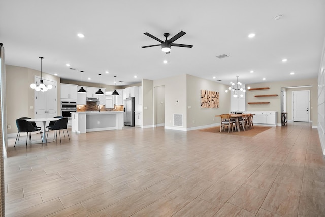 living room featuring ceiling fan with notable chandelier, baseboards, visible vents, and recessed lighting