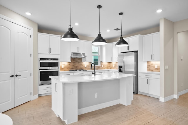 kitchen featuring a sink, backsplash, under cabinet range hood, light countertops, and appliances with stainless steel finishes