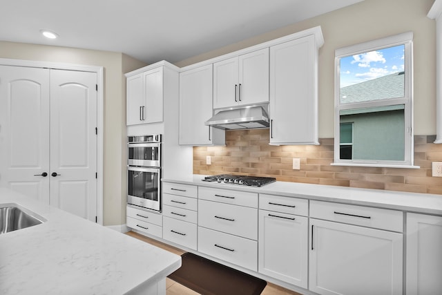kitchen featuring white cabinetry, tasteful backsplash, appliances with stainless steel finishes, and under cabinet range hood