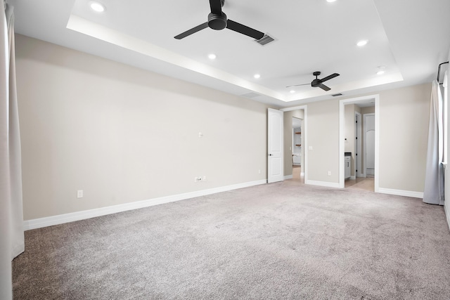 unfurnished bedroom featuring recessed lighting, baseboards, visible vents, a raised ceiling, and light carpet