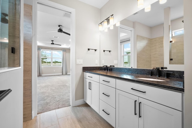 full bath featuring double vanity, baseboards, ceiling fan, and a sink