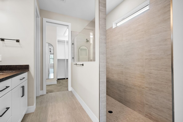 full bath with baseboards, vanity, and a walk in shower