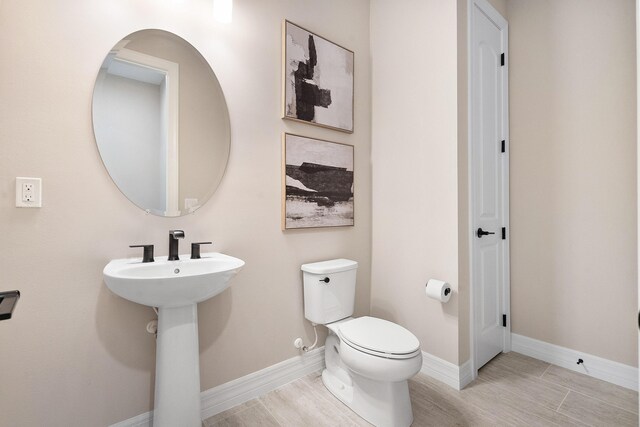 bathroom featuring toilet, baseboards, and wood finished floors