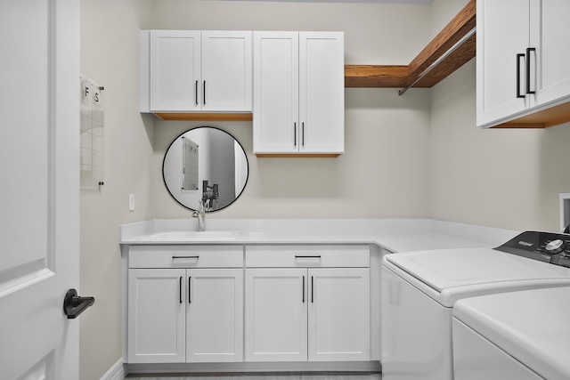 laundry area with cabinet space, separate washer and dryer, and a sink