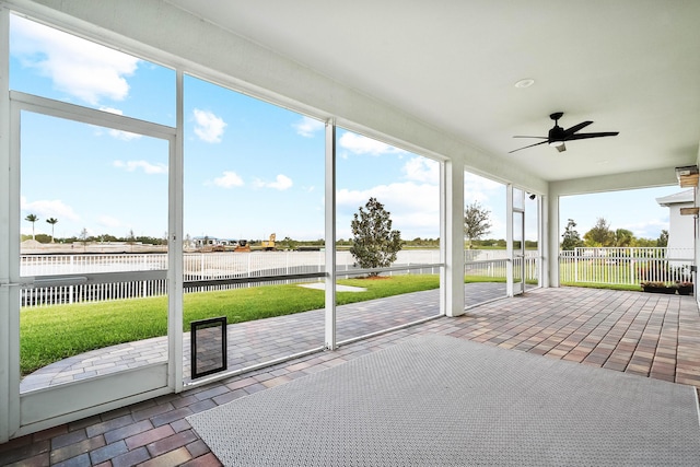 unfurnished sunroom featuring a water view and a ceiling fan