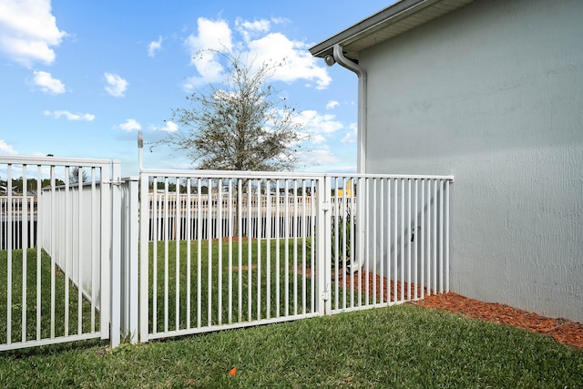 view of gate featuring fence and a lawn