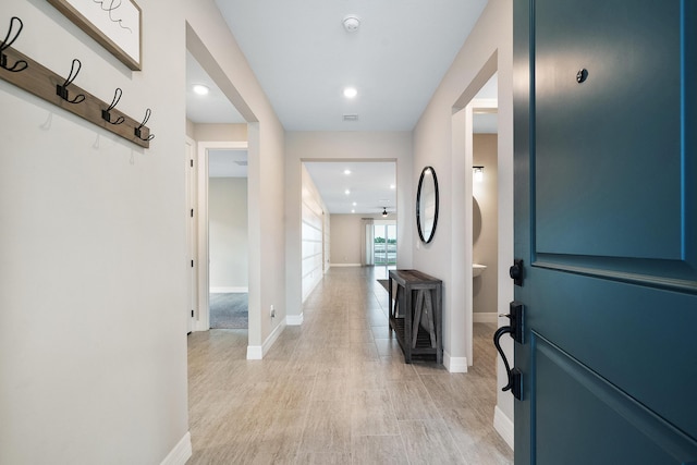 hallway featuring baseboards, light wood-type flooring, and recessed lighting