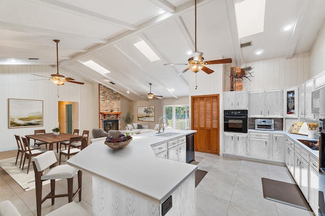 kitchen with black appliances, lofted ceiling with beams, a ceiling fan, and a sink