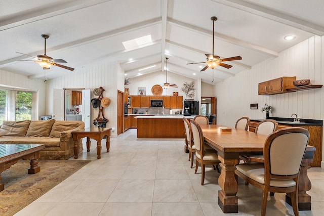 dining space featuring wooden walls, ceiling fan, and vaulted ceiling with beams