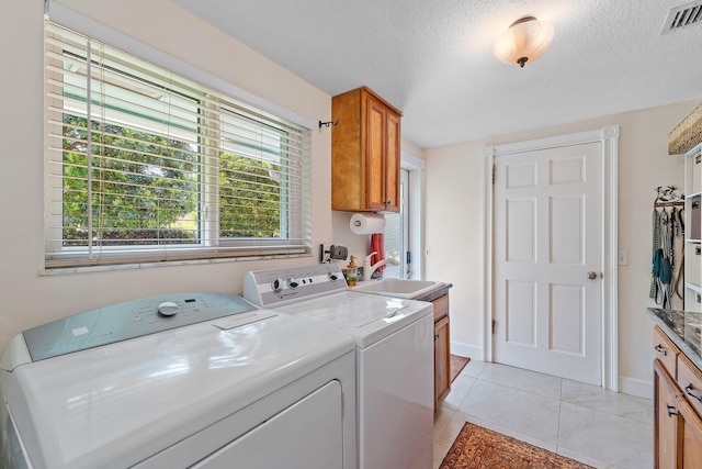 laundry area featuring a textured ceiling, visible vents, washing machine and dryer, cabinet space, and a sink