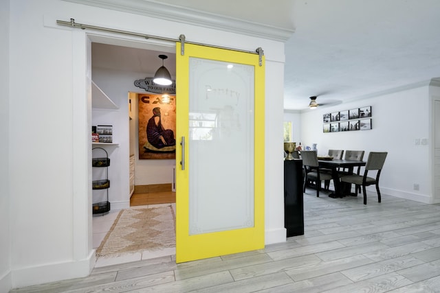 1050 Singer Dr, Singer Island, FL 33404 - interior space featuring a barn door, baseboards, ornamental molding, and light wood-style floors