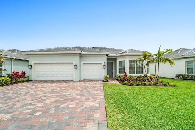 view of front of property featuring a tiled roof, a front yard, decorative driveway, an attached garage, and stucco siding