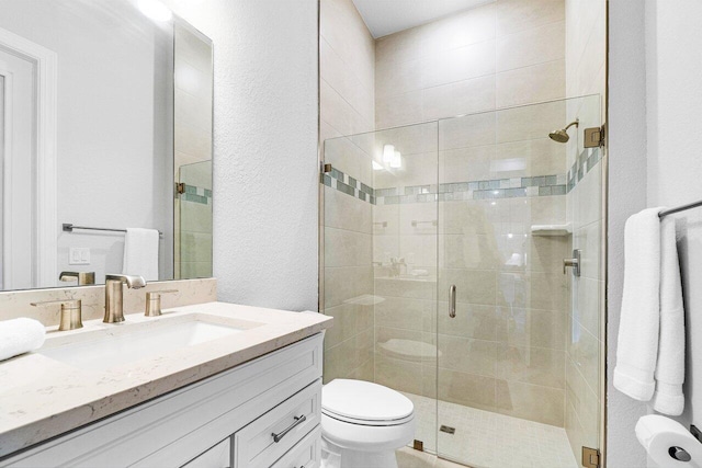 full bathroom with vanity, a textured wall, toilet, and a shower stall