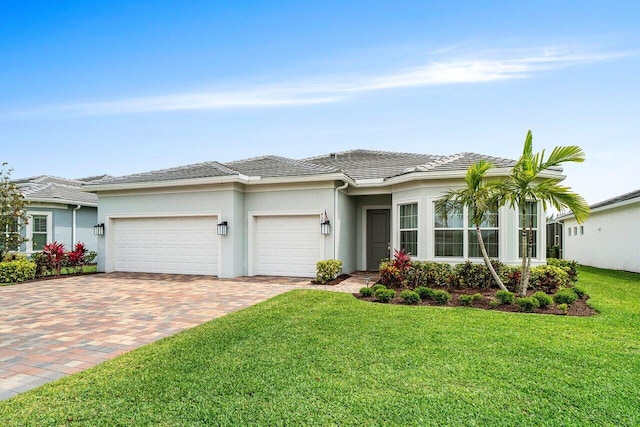 view of front of home with a tile roof, a garage, stucco siding, a front yard, and decorative driveway