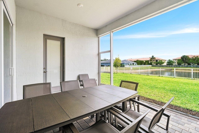 sunroom featuring outdoor dining area and a water view