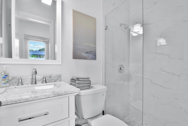 bathroom with a marble finish shower, vanity, and toilet