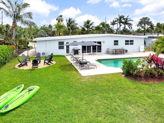 back of property featuring a yard, a patio, fence, and an outdoor fire pit