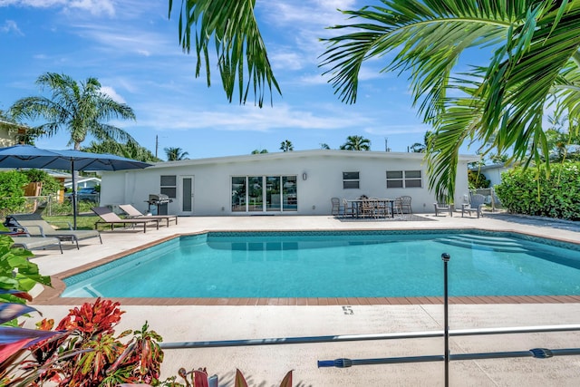 pool with area for grilling, a patio, and fence