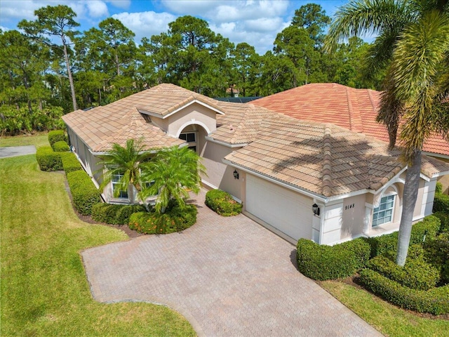 mediterranean / spanish home with stucco siding, a tiled roof, a garage, driveway, and a front yard