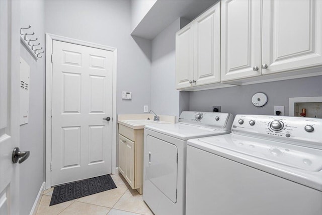 laundry room featuring light tile patterned floors, a sink, baseboards, washer and dryer, and cabinet space