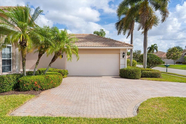 view of front of property with a garage, a tile roof, stucco siding, and decorative driveway