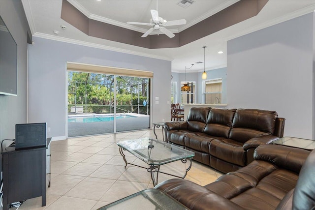 living area with light tile patterned floors, ceiling fan, visible vents, crown molding, and a tray ceiling