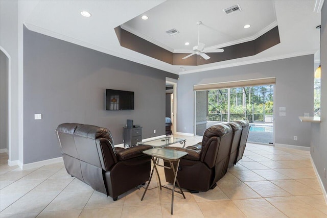 living area featuring crown molding, ceiling fan, a tray ceiling, baseboards, and light tile patterned flooring