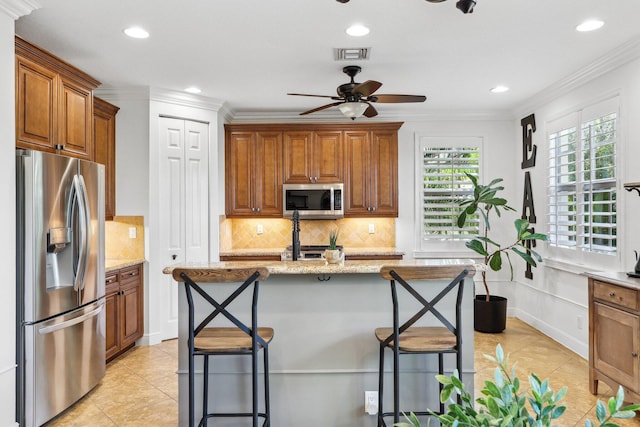kitchen with decorative backsplash, ceiling fan, brown cabinets, and stainless steel appliances