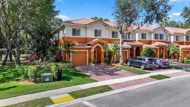 mediterranean / spanish house with a garage, decorative driveway, stucco siding, and a tiled roof