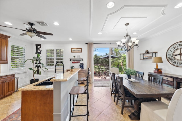kitchen featuring visible vents, brown cabinetry, an island with sink, and light tile patterned floors
