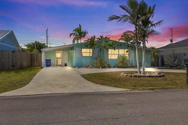 ranch-style home featuring driveway, a yard, and fence