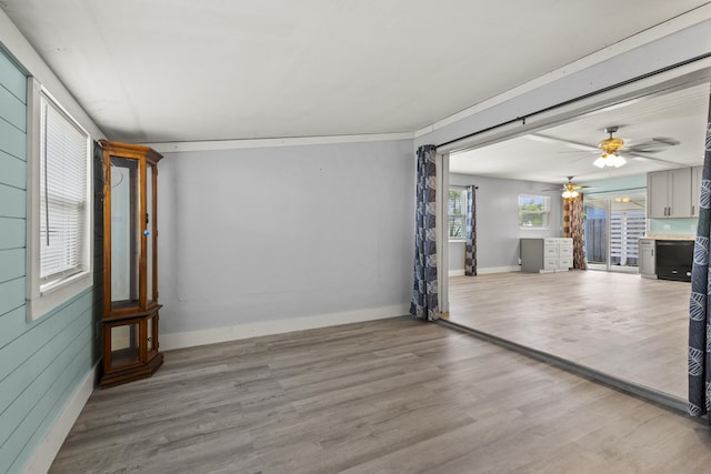 unfurnished living room with wood finished floors, baseboards, and ceiling fan