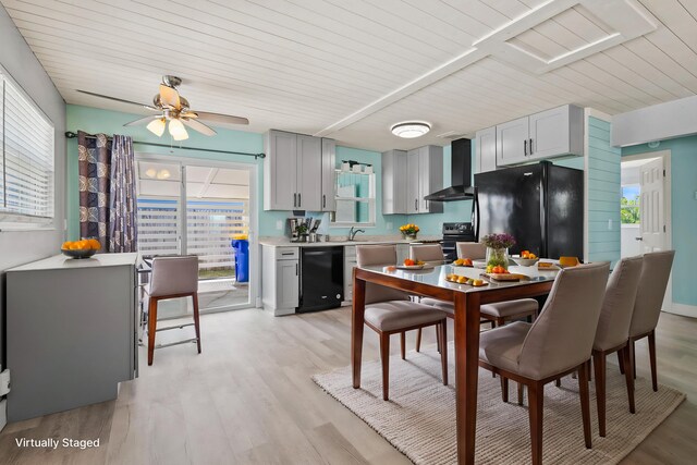 kitchen featuring black appliances, wall chimney range hood, light countertops, and plenty of natural light