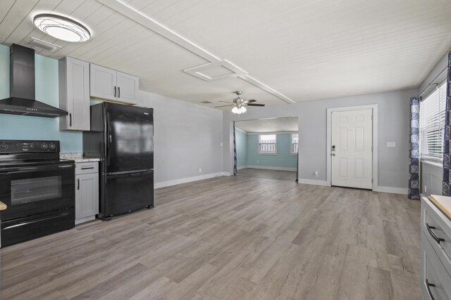 kitchen with plenty of natural light, wall chimney range hood, baseboards, and black appliances