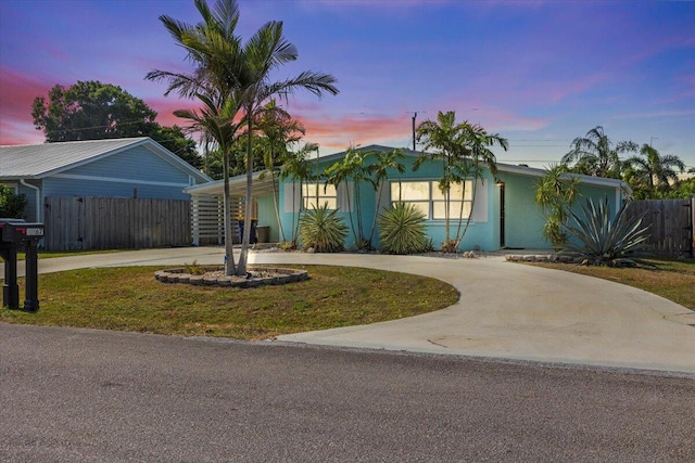 view of front facade featuring a front lawn, curved driveway, and fence