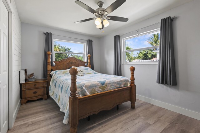 bedroom with baseboards, a ceiling fan, light wood-style floors, and multiple windows