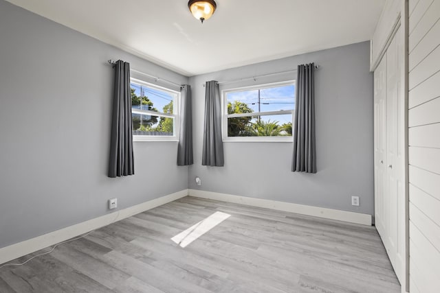 unfurnished room with light wood-type flooring and baseboards